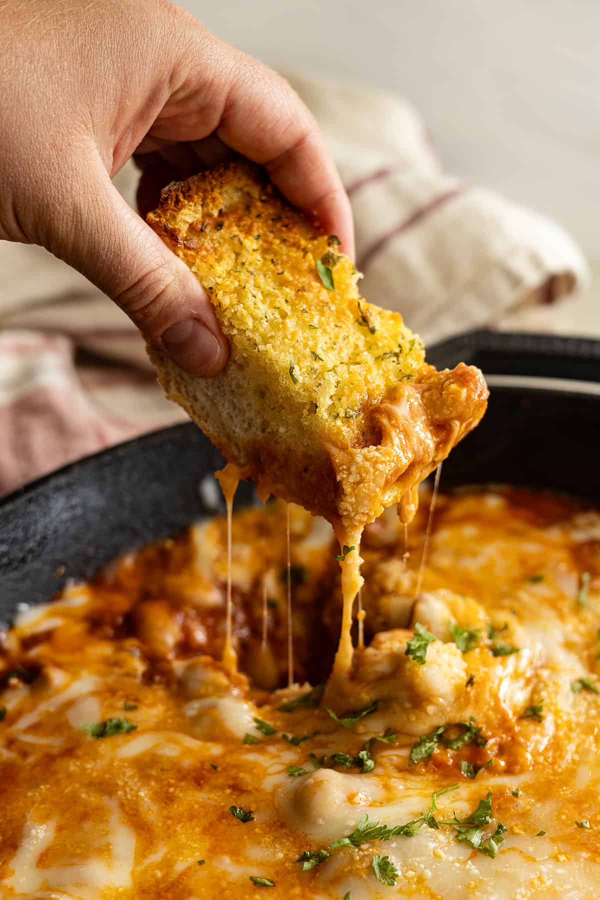 A piece of garlic bread being dipped into pizza beans.