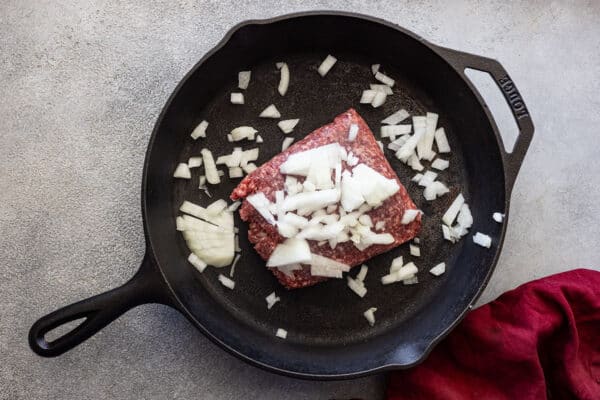Picture of ground beef and onion in a cast iron skillet.