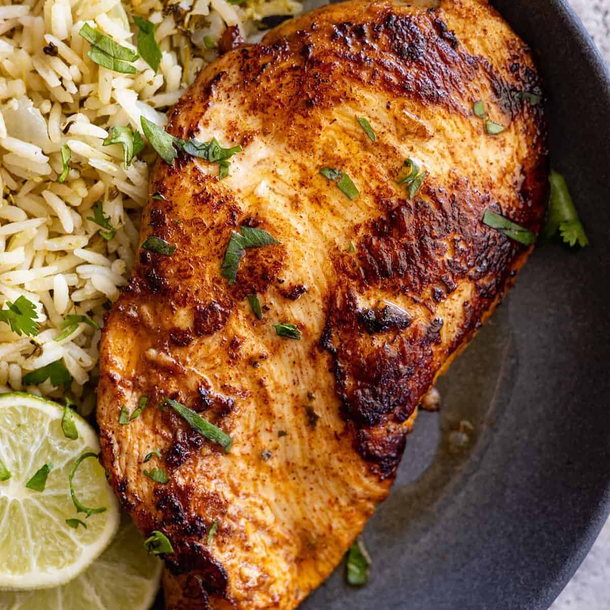 Overhead view of chicken on a blue plate with rice off to the side.