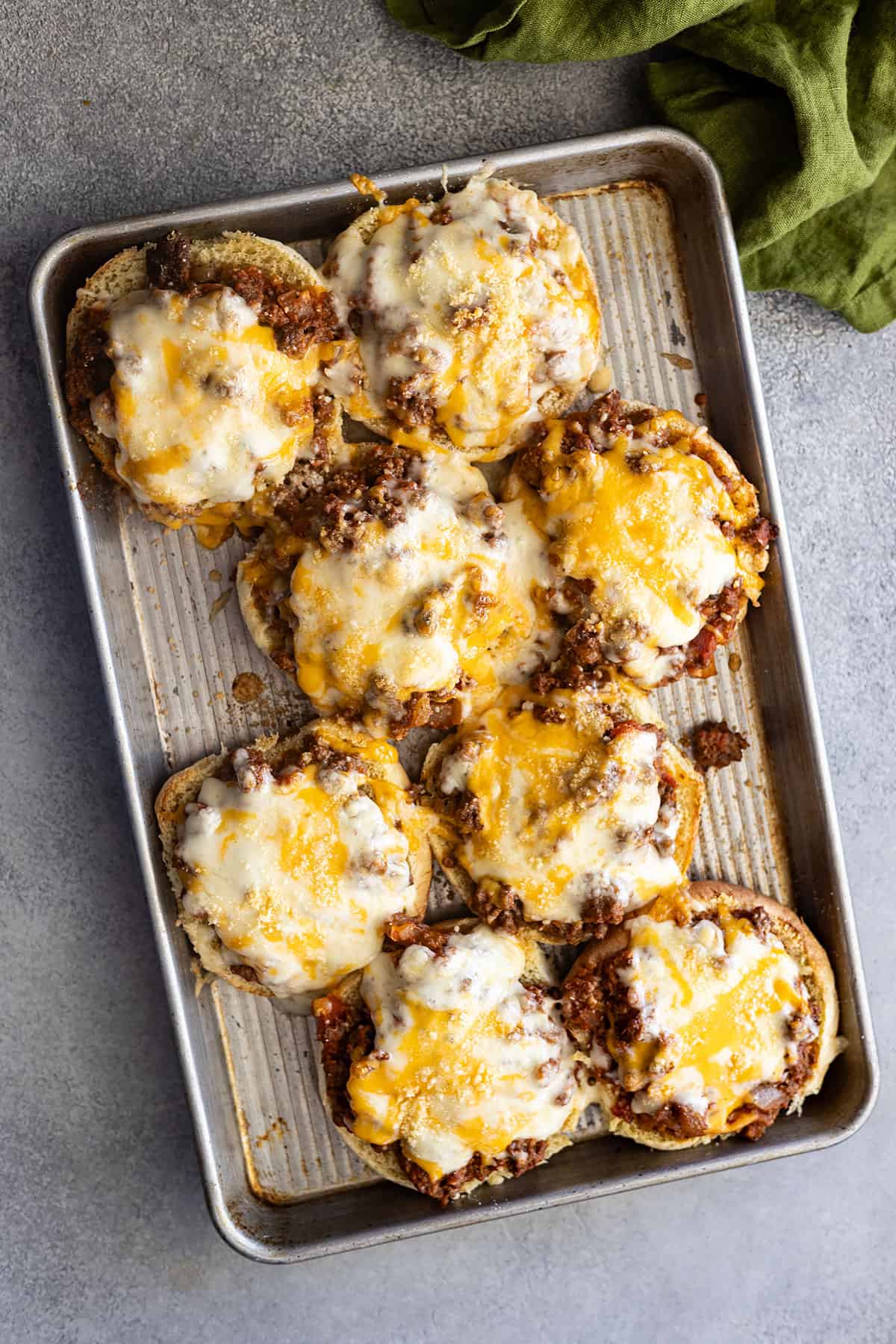 Overhead view of pizzawiches on a baking sheet fresh from the oven. Cheese is all melted and gooey.